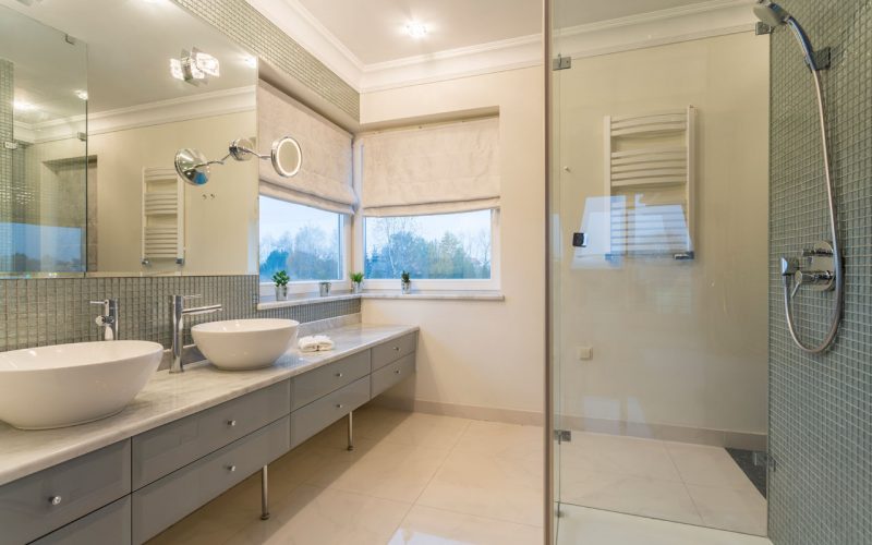 Spacious white bathroom with glass door shower and two sinks